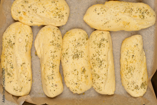 Obraz na płótnie A close-up shows several golden-brown bread rolls seasoned with garlic and oregano, suggesting a flavorful and aromatic baked good w salonie