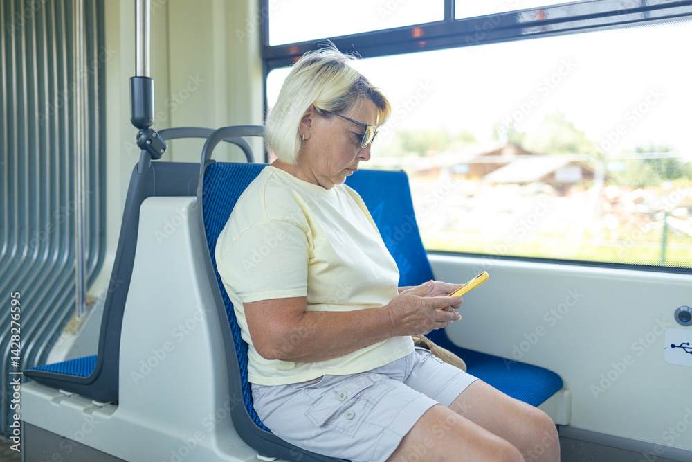 Old European woman sitting in streetcar and using smartphone while waiting for next stop and going home. High quality photo