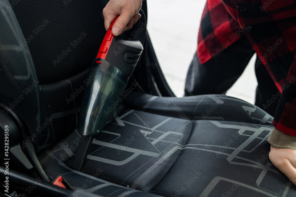 Details of car vacuum cleaning. Professional cropped male worker using wet vacuum cleaner for dirty car interior. Auto car service cleaning the drivers seat, cleaning and vacuuming concept. High