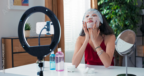 Online creator demonstrates face mask application and talks about her favorite beauty products. Livestream filmed using ring light and phone on tripod at home.