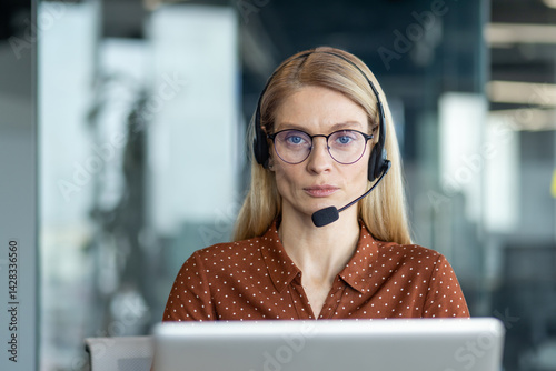Obraz na płótnie A professional woman with blonde hair and glasses wearing a headset, ready to provide customer service. She appears focused and attentive, facing the camera. w salonie