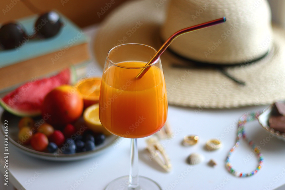 Glass of cocktail, straw hat, sunglasses, books, fresh fruit, chocolate and accessories. Summer essentials on the table. Selective focus.