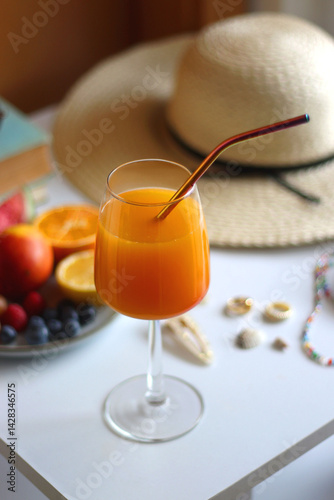 Glass of cocktail, straw hat, sunglasses, books, fresh fruit, chocolate and accessories. Summer essentials on the table. Selective focus.