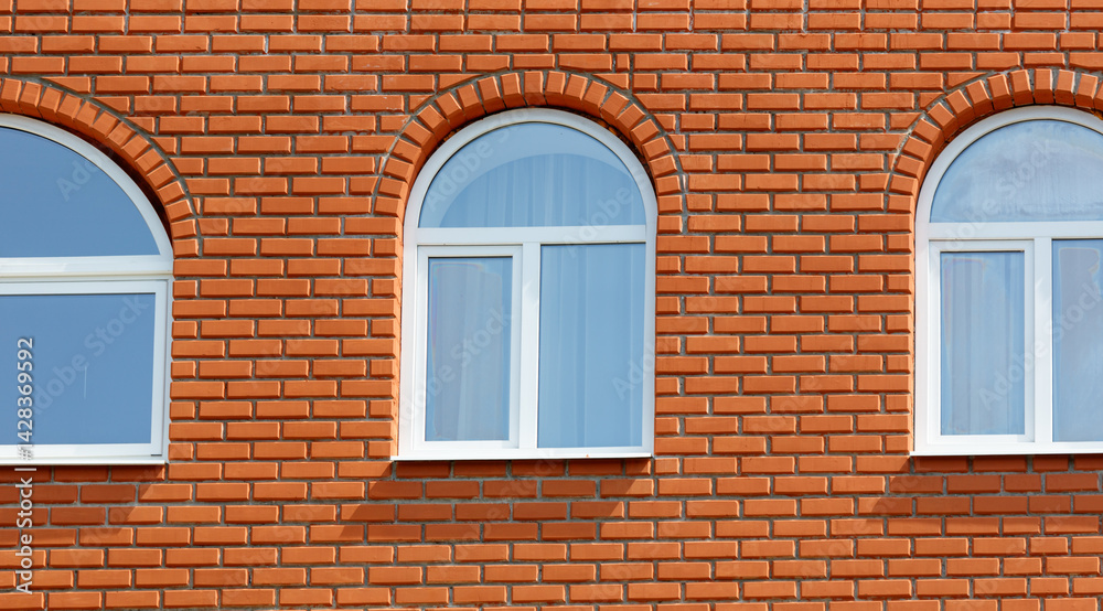 Fototapeta premium Three windows on a brick wall with a white trim