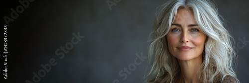 Obraz na płótnie Confident mature woman with long silver wavy hair smiling gently against dark blurred background in soft natural lighting Generative AI w salonie