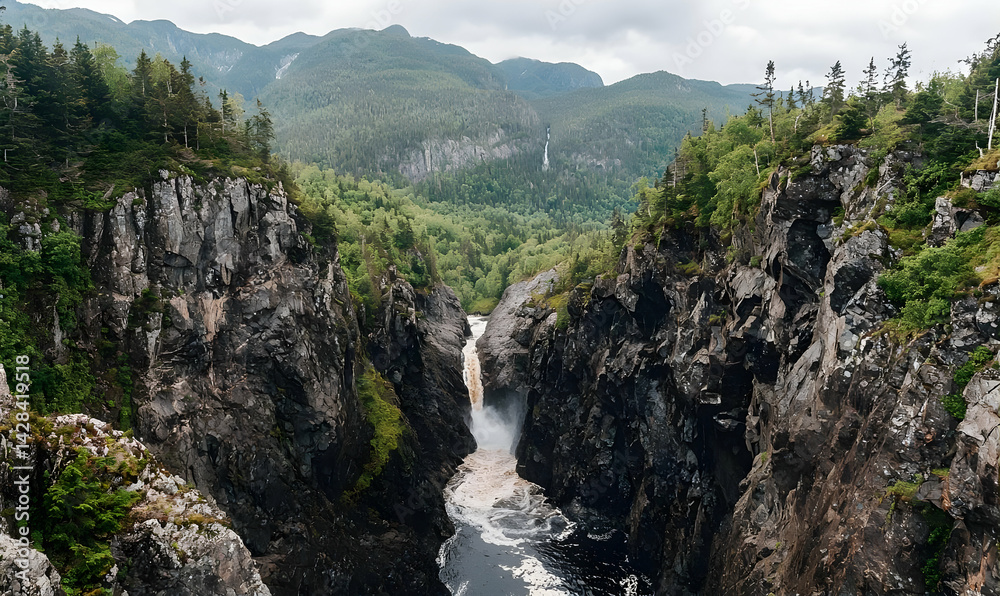 Obraz premium Majestic Waterfall Plunging Through Rugged Cliffs in a Verdant Valley