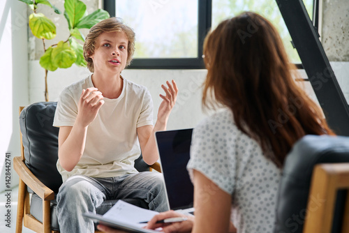 Teenage boy talking to female professional psychologist counselor therapist photo