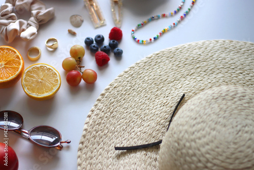 Straw hat, sunglasses, seasonal fruit, seashells and colorful accessories on white backgrounds. Cute summer essentials. Selective focus.