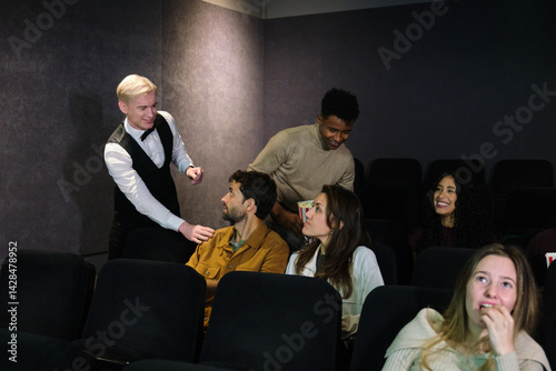 Obraz na płótnie Movie theater employee guiding people to their assigned seats while other spectators are already watching the film w salonie