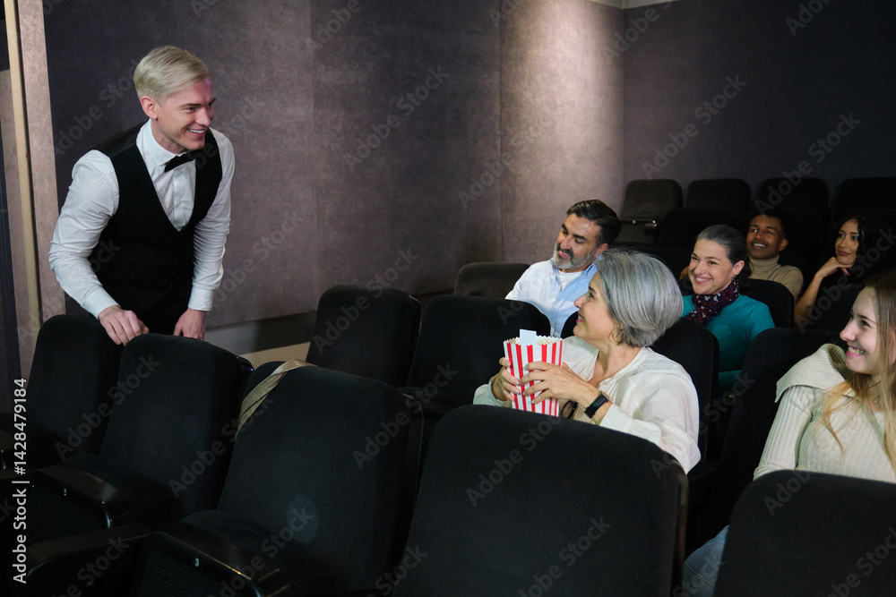 Usher welcoming spectators showing seats in a movie theater and smiling