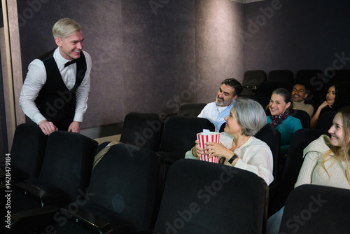 Obraz na płótnie Usher welcoming spectators showing seats in a movie theater and smiling w salonie