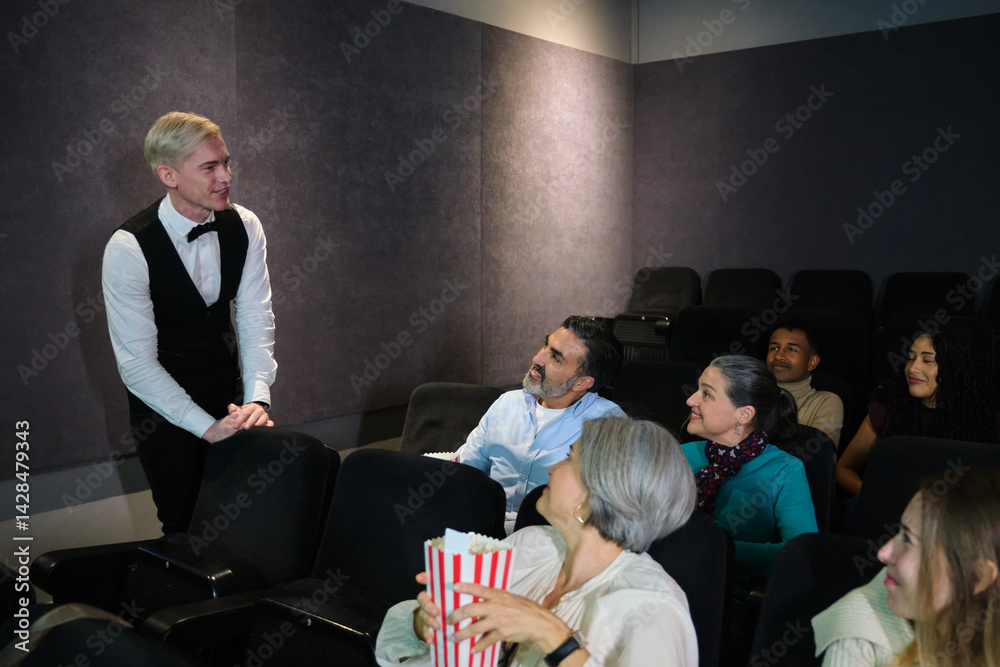 Diverse audience enjoying popcorn and movie presentation by cinema employee in a movie theater
