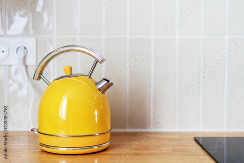 Bright yellow kettle on a wooden countertop in a modern kitchen setting