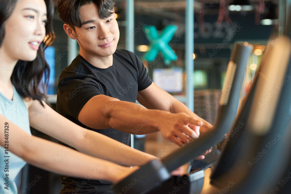 Young Asian Man and Woman Exercising Together at Gym Young Asian Man and Woman Exercising Together at Gym