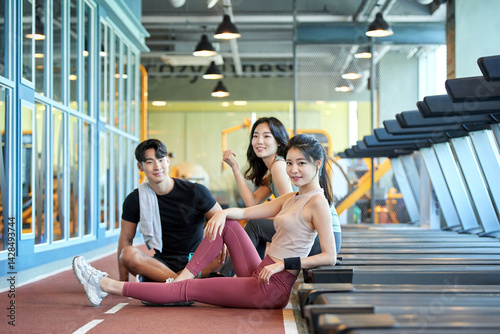 Two Asian Women and One Asian Man Relaxing at Gym