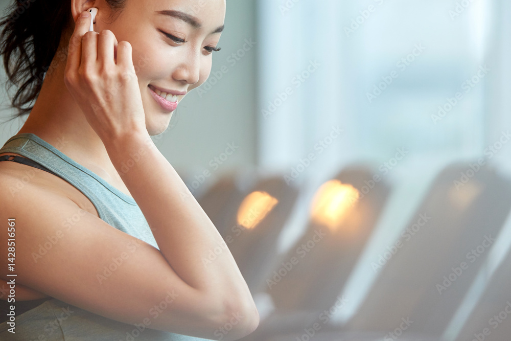 Asian Woman Smiling with Earbuds at Gym Asian Woman Smiling with Earbuds at Gym