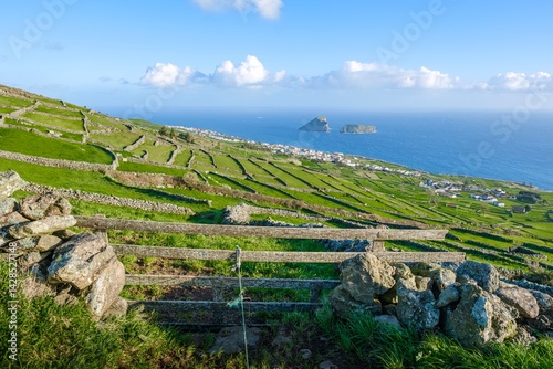Coastal Panorama from Highland Pastures with Ancient Stone Walls and Wooden Fence. Spectacular View of Coastal Settlement and Dramatic Offshore Islets in Sao Jorge Island, Azores Archipelago