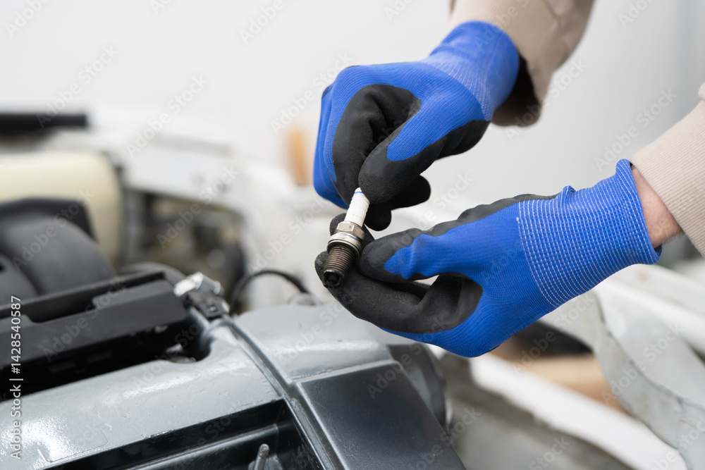 A car mechanic works on an engine, replacing a spark plug in an auto repair shop A car mechanic works on an engine, replacing a spark plug in an auto repair shop