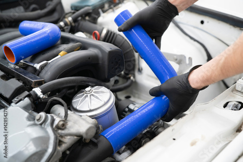 Wallpaper Mural Mechanic replaces silicone hose in the engine compartment of a vehicle, ensuring proper fit and function Torontodigital.ca