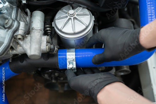 Wallpaper Mural A car mechanic uses a metal clamp to secure a blue hose while performing maintenance in an auto repair shop. Torontodigital.ca