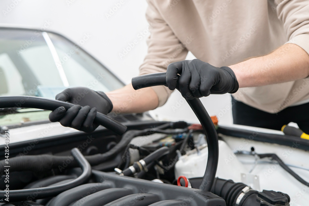 Mechanic works on installing air hose inside the engine compartment of a vehicle, ensuring proper function at an auto repair shop. Mechanic works on installing air hose inside the engine compartment of a vehicle, ensuring proper function at an auto repair shop.