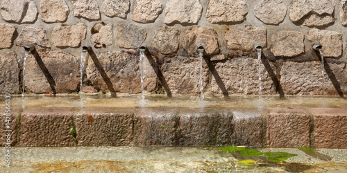 Fontaine avec six tuyaux déversant l'eau dans un bassin de pierre
