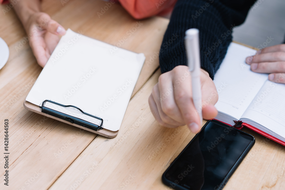 Cropped image of caucasian man holding pen for writing ideas and planning project with female colleague sitting at table, top view of male and female students making research and strategy for project