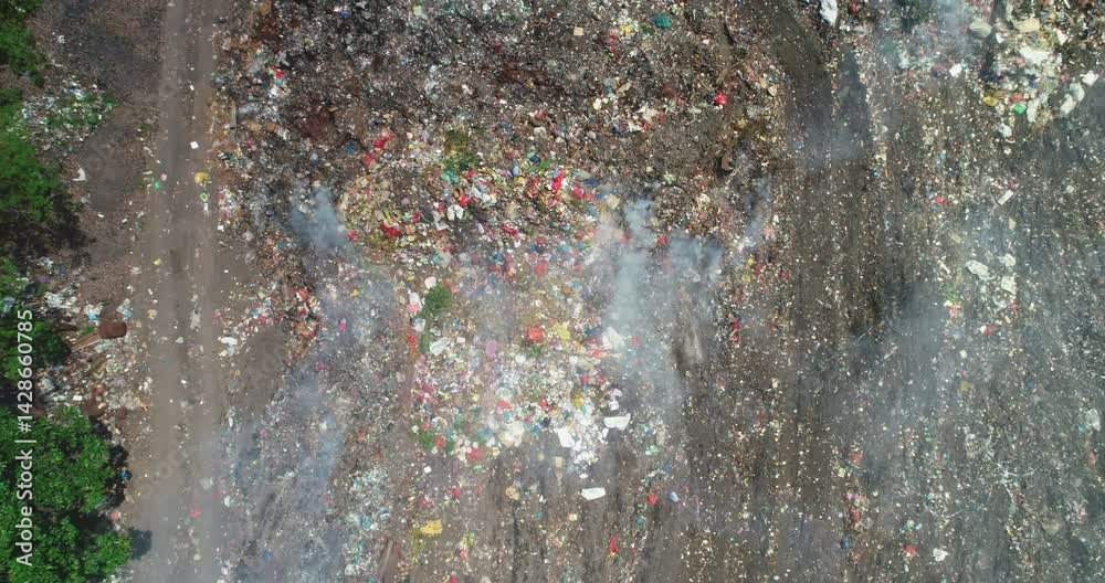 Aerial view of a smoking garbage dump with plastic waste causing air pollution in Ende, Flores island, Indonesia, highlighting environmental damage and waste management issues