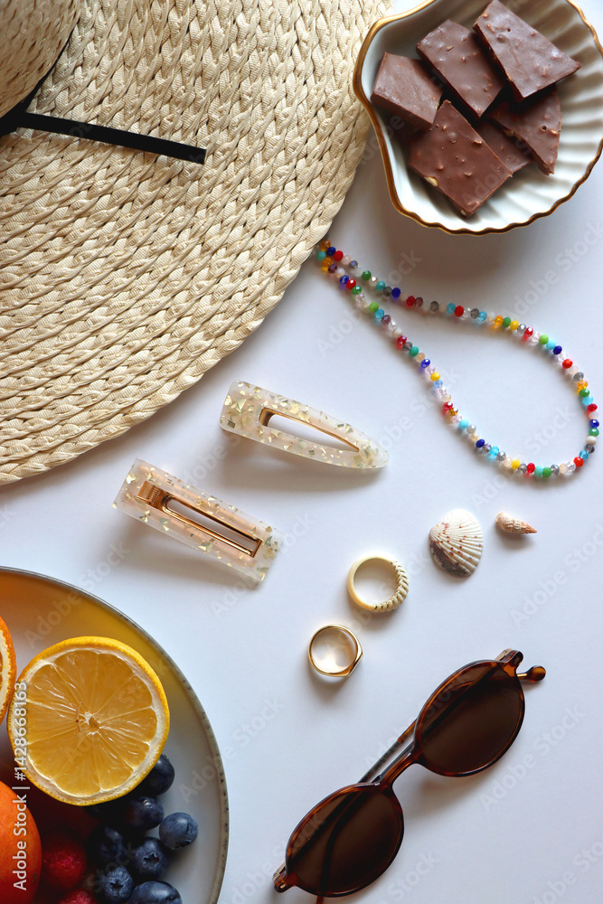 Glass of cocktail, straw hat, sunglasses, books, fresh fruit, chocolate and accessories. Summer essentials on the table. Top view.