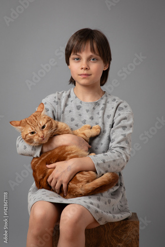 Obraz na płótnie Studio portrait of adorable little girl holding and hugging red cat. w salonie