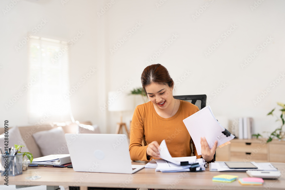 Woman holding document file stack of business document paper looking at laptop computer flicking through clients files on table, searching for and picking a file in home office. Woman holding document file stack of business document paper looking at laptop computer flicking through clients files on table, searching for and picking a file in home office.