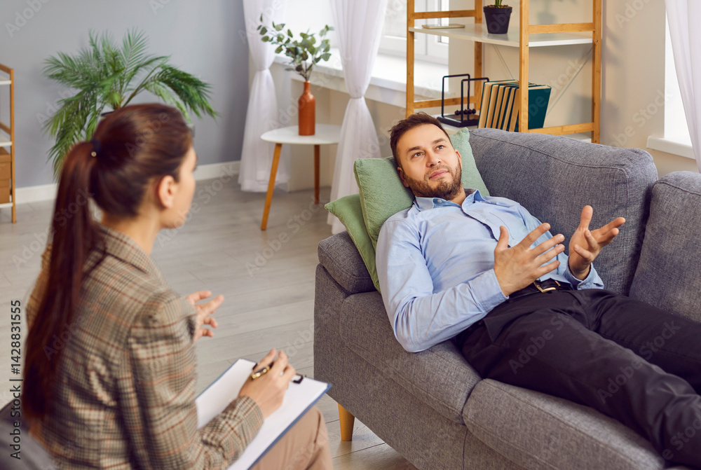 Adult male patient talking to counseling psychologist at therapy session. Young man lying on sofa, sharing thoughts with female therapist, expressing doubt, asking for advice. Psychotherapy concept