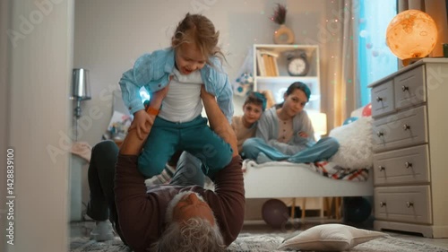 Grandson and grandfather playing aiplanes together on the floor at home. Senior man holding excited little boy smiling while playing a flying game. photo