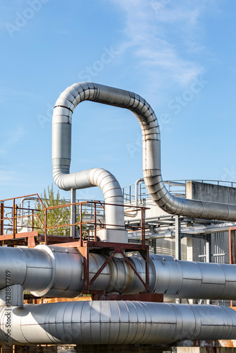 Rohrleitung zur Wärmeversorgung und Flüssigkeitsleitung in einem industriellen Komplex vor blauem Himmel