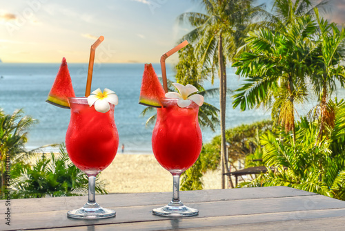 Fototapeta Naklejka Na Ścianę i Meble -  Two red drinks with melon garnish on a tropical beach