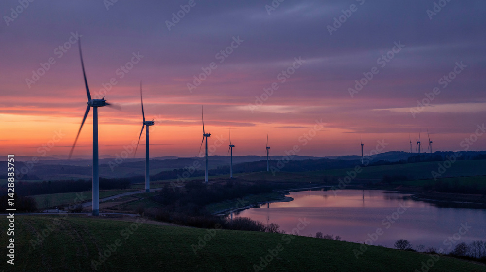 Obraz premium Wind turbines spin slowly against a colorful dusk horizon!