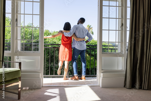Wallpaper Mural Standing Asian and African American couple hugging on tiled balcony, with white French doors Torontodigital.ca