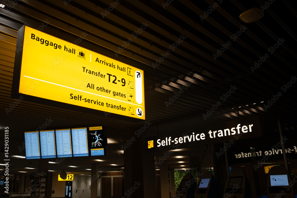 Airport terminal showing direction signs for baggage, arrivals, and transfer gates
