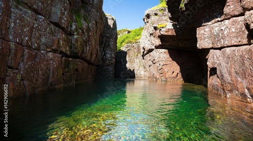 A serene, rocky inlet with clear turquoise waters surrounded by steep cliffs and lush greenery, creating a tranquil natural landscape.