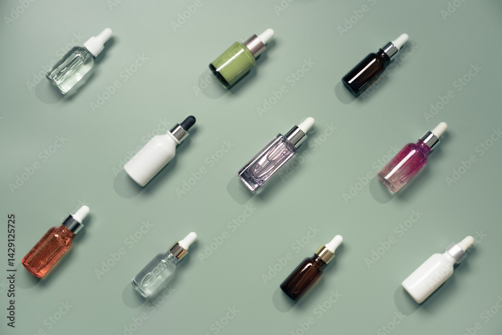 Different glass bottles with serum or oil on green background. Trending shadow. Cosmetic mockup. Top view with copy space. Flat lay.