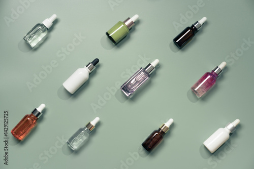 Obraz na płótnie Different glass bottles with serum or oil on green background. Trending shadow. Cosmetic mockup. Top view with copy space. Flat lay. w salonie