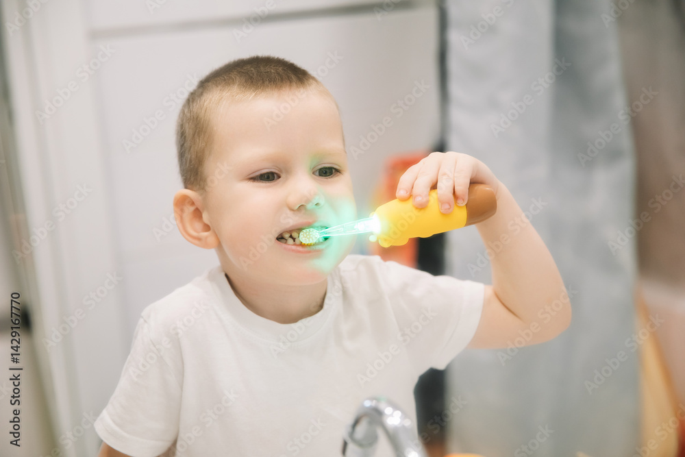 boy brushing teeth in bathroom in front of mirror. oral and dental hygiene. children's toothbrush with backlight boy brushing teeth in bathroom in front of mirror. oral and dental hygiene. children's toothbrush with backlight