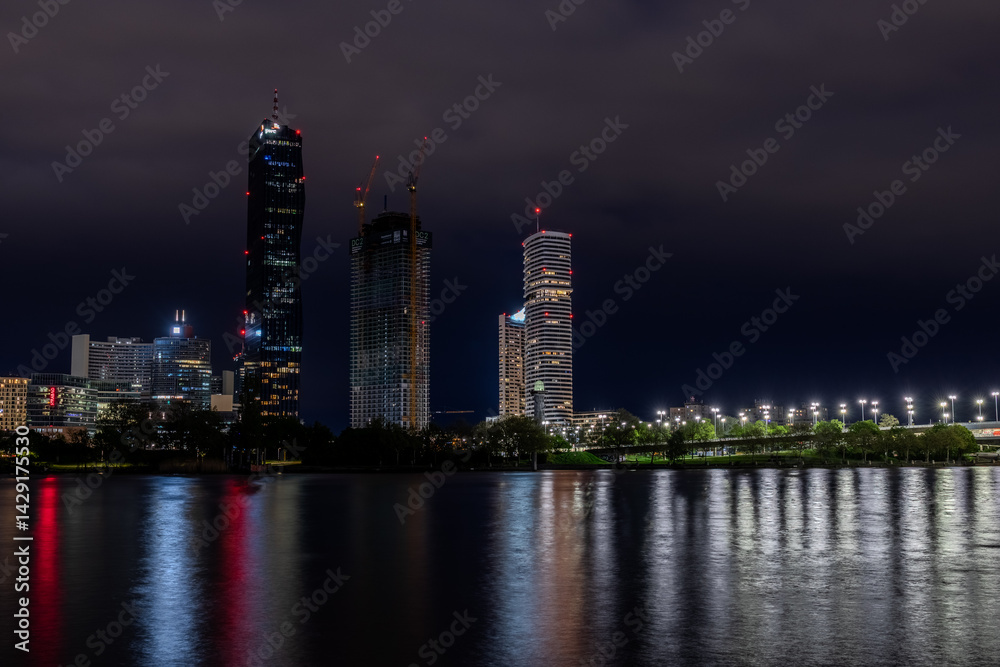 Obraz premium Night view of skyscrapers in Vienna from the bank of the Danube with reflections