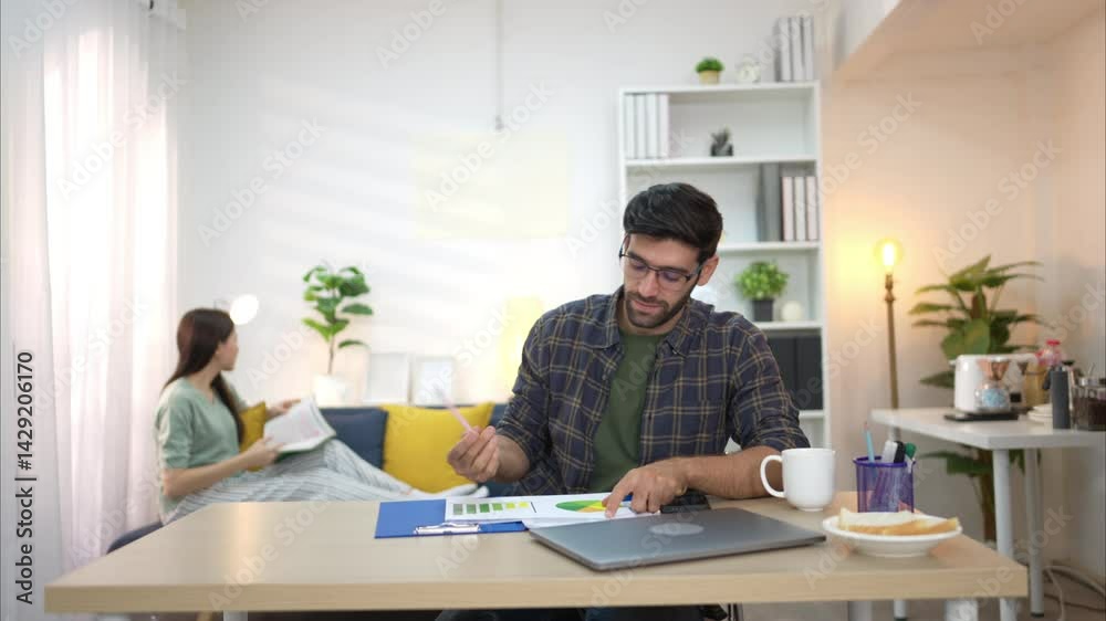Portrait of a young freelancer smiling while working online via laptop at home with his girlfriend Portrait of a young freelancer smiling while working online via laptop at home with his girlfriend