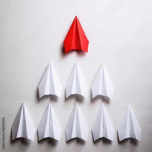 Red paper airplane leading white planes in formation on white background