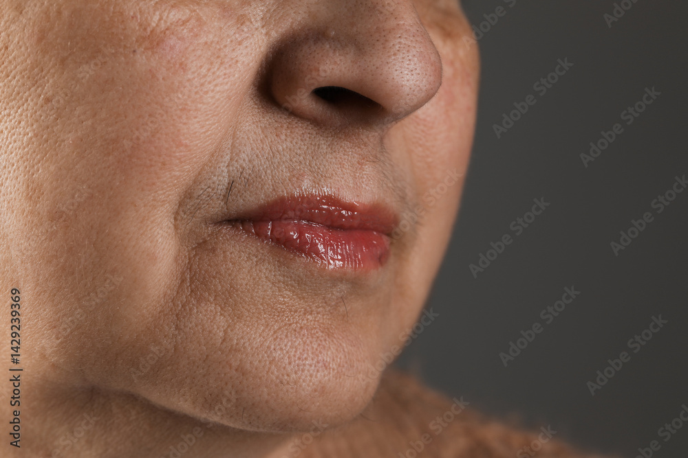Obraz premium Senior woman with mustache on grey background, closeup. Space for text