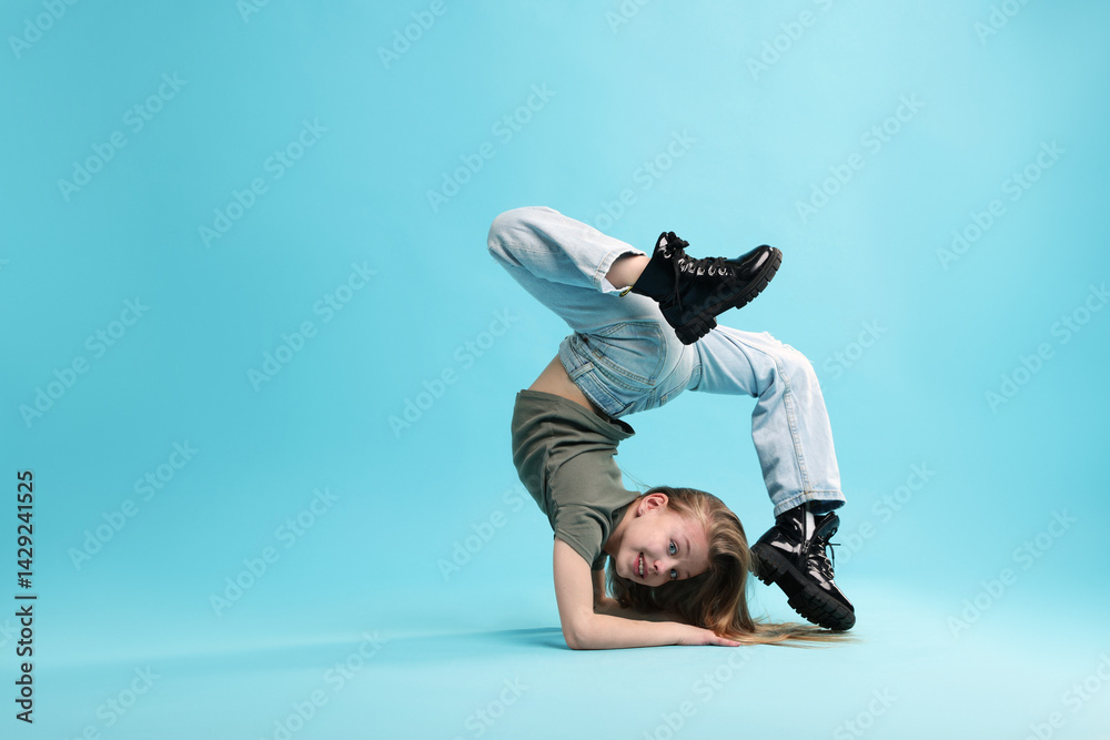 Girl in stylish clothes dancing on light blue background, space for text