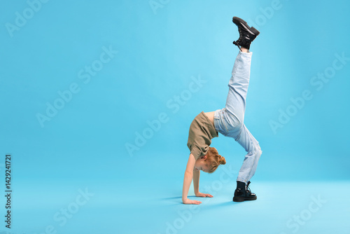 Obraz na płótnie Girl in stylish clothes dancing on light blue background, space for text w salonie