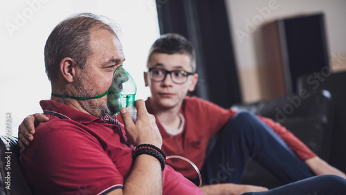 Middle-aged man using oxygen mask at home for breathing treatment