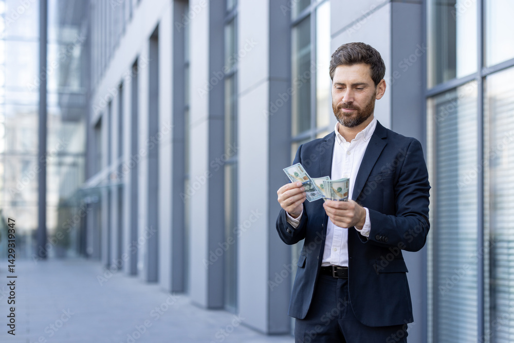 A businessman in a suit counts money in front of a modern building, highlighting wealth and financial success. The man appears thoughtful as he handles the cash.